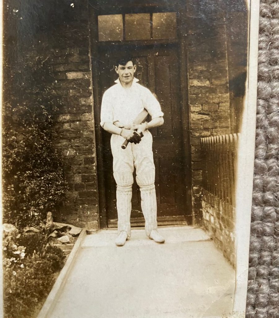Photograph of a cricketer , John G Lake, in front of a doorway