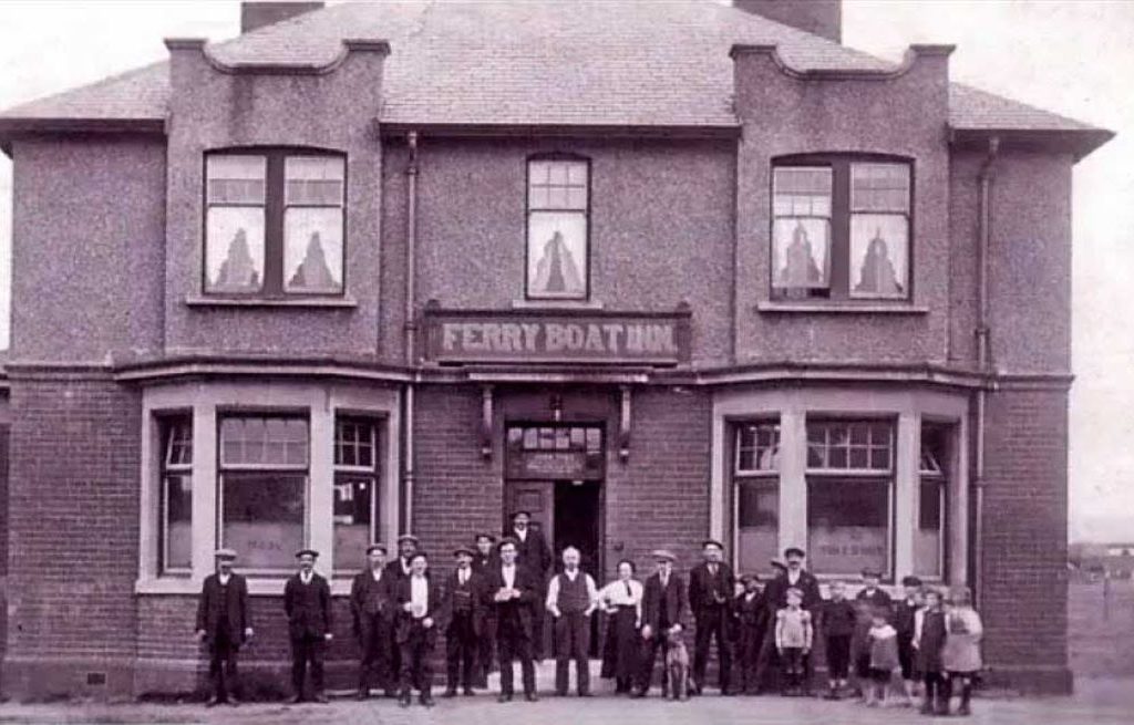 Image of the Ferry Boat Inn showing a group of men, women and children plus a dog in the foreground